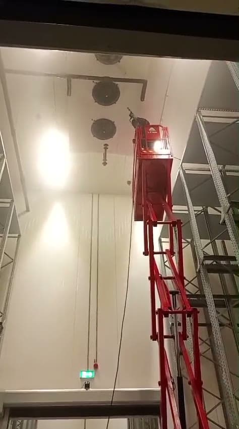Ventilatoren in een hoge koelhal worden gereinigd vanaf een hoogwerker